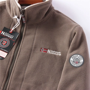 Close-up of brown fleece jacket with warm white shearling lining and chest embroidery detail