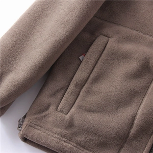 Macro detail of brown fleece jacket showing side pocket stitching and adjustable hem drawstring