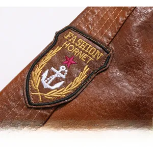 Detailed close-up of brown PU leather jacket arm with embroidered fashion shield patch