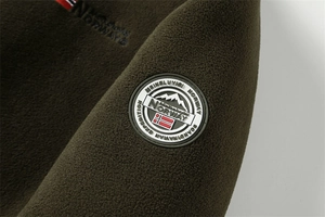 Detail of Norway rubber badge and olive green polar fleece texture on thermal men's jacket