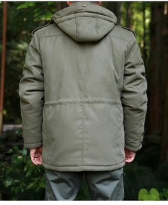 Rear view of an olive green hooded parka jacket for men in a forest setting