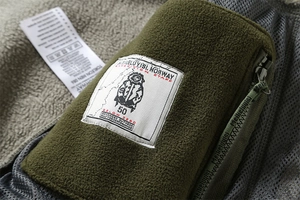 Detail of army green fleece jacket featuring polar adventure woven label and zip pocket