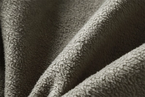 Macro close-up of thick dark grey polar fleece fabric texture for thermal winter jackets