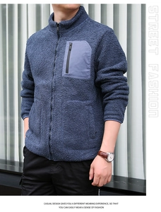 Detail of navy fleece jacket featuring high collar and grey contrast chest zipper pocket