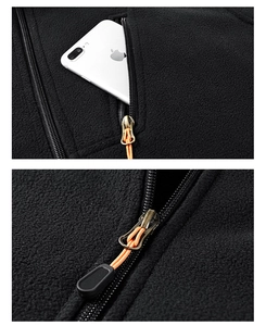 Detailed macro shot of black fleece jacket with zipper pocket and orange pulls