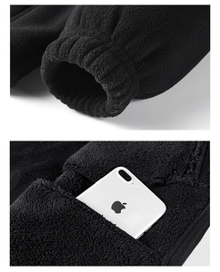 Detail of fleece jacket showing elastic cuffs and large zipper pocket with a phone inside