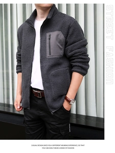 Detail of grey sherpa fleece jacket featuring a charcoal zip chest pocket and stand collar