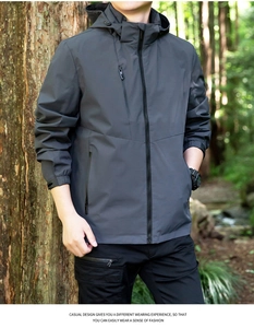 Detail of dark grey outdoor jacket featuring zipper pockets and elastic cuffs in nature