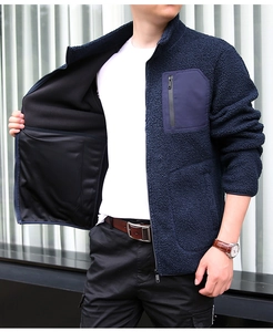 Detail of navy fleece jacket featuring a high collar, zip pocket, and warm woolly texture