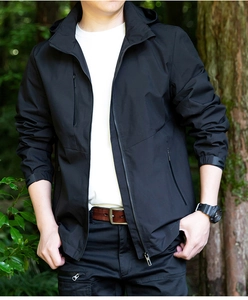 Outdoor close-up of a black waterproof jacket with a hood and adjustable velcro cuffs