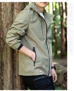 Detail of hooded windproof outdoor jacket in sage green with zippered side pockets