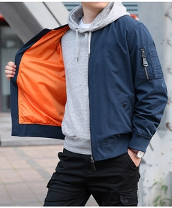 Détail d'un blouson bomber bleu avec doublure orange, bords-côtes et poche de manche
