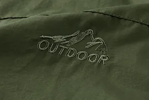 Macro detail of mountain embroidery and twill fabric on thick green outdoor jacket