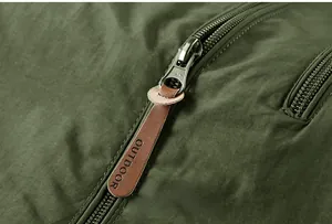Macro detail of a high-quality metal zipper and embossed leather pull on an outdoor jacket