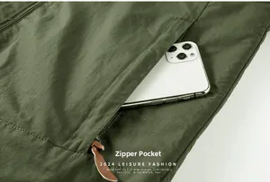 Detail of army green waterproof jacket featuring zippered pocket with leather puller