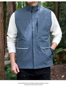 Detail of dark grey outdoor vest featuring a stand collar and multiple functional zip pockets