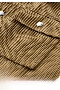 Close-up of brown corduroy fabric jacket featuring a flap pocket and metallic button detail