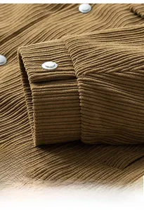 Detailed close-up of corduroy jacket cuff with metallic silver button and ribbed texture