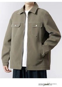 Detail of olive green jacket with metal zipper and decorative white stitching on pockets