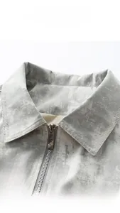 Dettaglio della giacca con motivo a marmo grigio, risvolto classico e zip in metallo