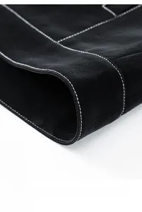 Detail of black pebbled leather hem with white contrast stitching on a men's jacket