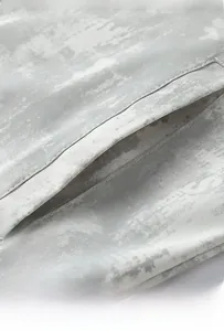 Dettaglio della tasca laterale su giacca mimetica grigia con cuciture e trama in twill