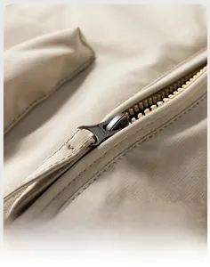 Detailed close-up of a high-quality metal zipper and stitching on a beige pilot jacket