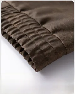 Detailed close-up of elastic hem design and vintage brown faux leather texture on the jacket