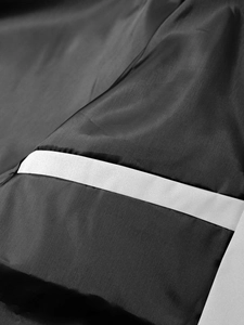 Macro shot of black tactical jacket fabric featuring a smooth grey reflective decorative strap