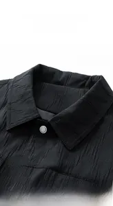 Detail shot of black lapel jacket showing textured fabric and silver metallic button