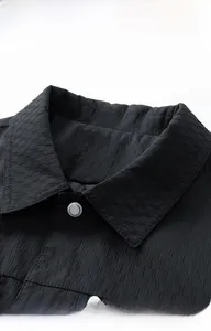 Detail of classic collar and silver metal button on black vertical textured jacket