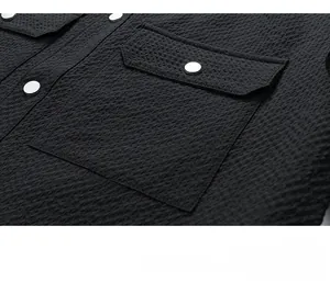 Detailed close-up of black waffle texture fabric and silver button on a men's jacket