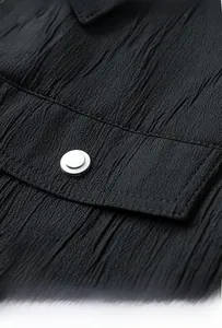 Detail of black crinkled fabric cargo jacket with chest pocket and metal button
