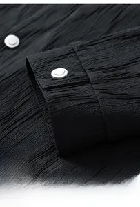 Detail of black crinkled texture fabric and metallic buttons on the jacket cuff