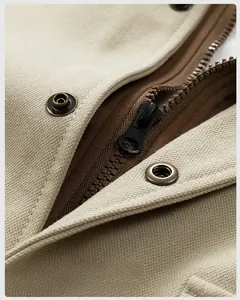 Detail view of high-quality black nylon zipper and vintage bronze metal snap buttons on jacket