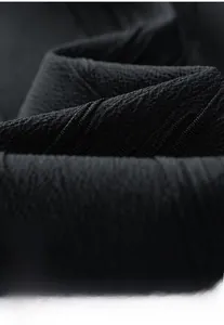 Macro shot showing the black textured fabric and high-quality knit grain of the men's jacket