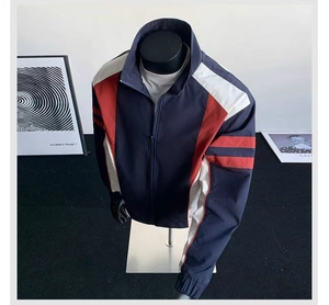 Detail of color-block windbreaker jacket showing navy blue fabric and red sleeve accents