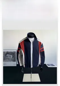Detail view of navy blue windbreaker jacket featuring red and white color blocking design