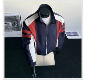 Detail of color-block jacket showing navy blue, white, and red panels with zipper closure