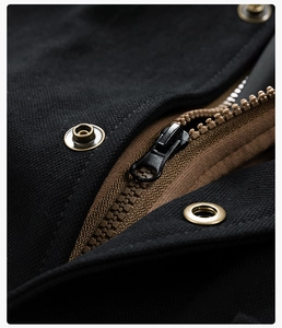Detail of metal zipper and bronze snap buttons on black workwear jacket with brown lining
