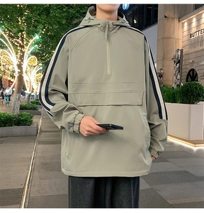Detail of celadon green pullover jacket featuring navy side stripes and large front pocket
