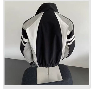 Detail view of back拼接 design on a tri-color windbreaker jacket in black grey and white