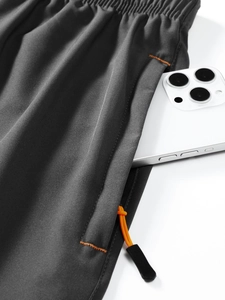 Detailed macro view of quick-dry shorts side pocket with contrast orange stitching and cord
