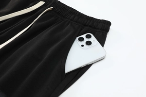 Close-up of black waffle fabric shorts with elastic waist and cream flat drawstring