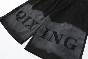Detail of black breathable mesh sports shorts featuring bold QIXING graphic print
