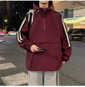 Close-up of windproof burgundy pullover jacket with contrast stripes and utility pocket