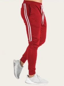 Détail d'un pantalon de jogging rouge avec doubles rayures et cordon de serrage