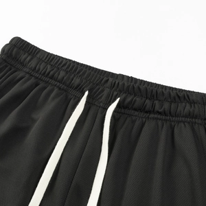 Detail of black breathable mesh sports shorts with elastic waist and white drawstrings