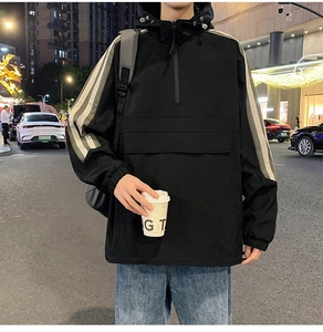 Detail of black hooded windbreaker with half-zipper, cargo pocket and striped sleeves