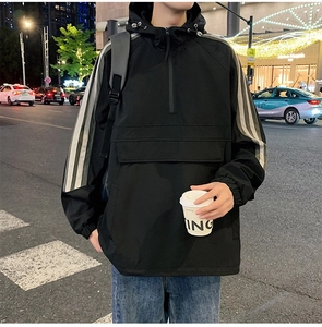 Detail of black windbreaker featuring a half-zip hood and white stripe sleeve accents